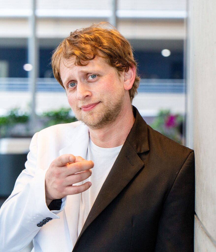 Josh Silverbauer, analytics and CRO consultant, pointing at the camera in a two-tone blazer